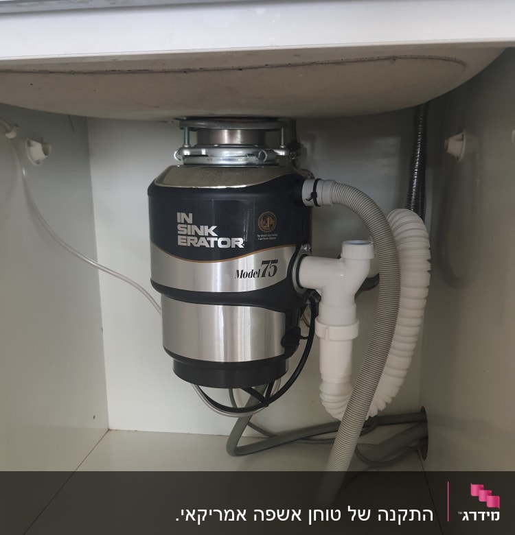מכשיר טוחן אשפה מותקן מתחת לכיור עם צינורות מחוברים